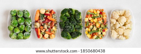 Set of frozen vegetables in plastic containers on a white background. Banner. View from above.