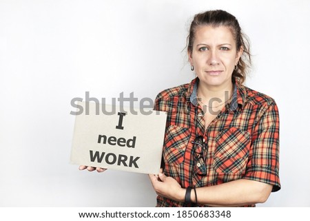 Middle-aged woman in simple clothes on a light background holding a sign in his hands, the sign has the inscription - I need a job, work. The woman lost her job because of quarantine