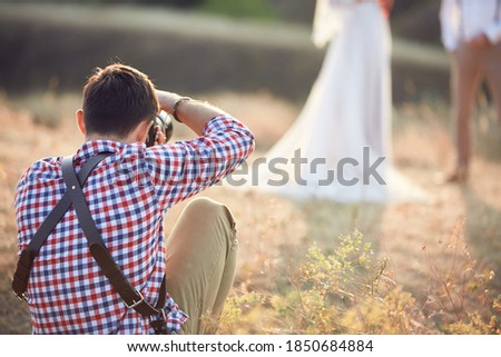 wedding professional photographer takes pictures of the bride and groom in nature on the sunset, man photographer in action