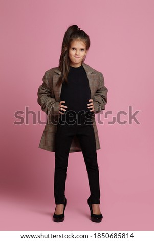 cute little child girl in white oversized mother's jacket and shoes on pink background. child playing businesswoman