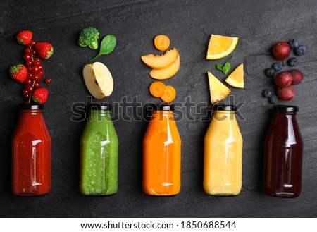 Flat lay composition with bottles of delicious juices and fresh ingredients on black table Royalty-Free Stock Photo #1850688544