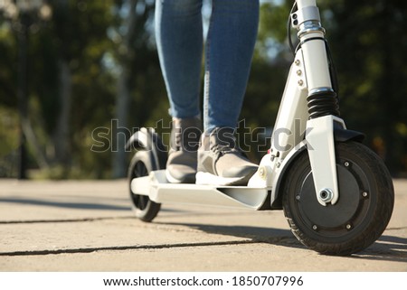 Woman riding electric kick scooter outdoors, closeup Royalty-Free Stock Photo #1850707996