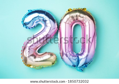 Rainbow foil balloon number, digit twenty. Birthday greeting card with inscription 20. Anniversary concept. Top view. Colored numeral on blue background. Numerical digit, Celebration event, template. Royalty-Free Stock Photo #1850732032