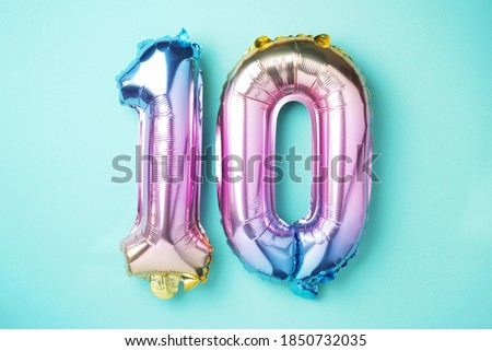 Rainbow foil balloon number, digit ten. Birthday greeting card with inscription 10. Anniversary concept. Top view. Colored numeral on blue background. Numerical digit, Celebration event, template. Royalty-Free Stock Photo #1850732035