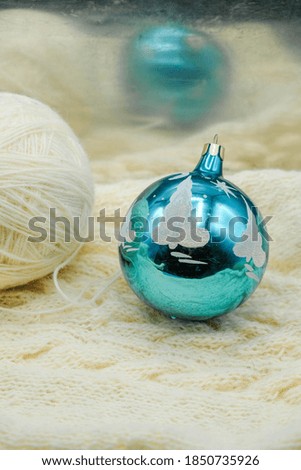 Aqua Christmas ball and a wool ball on a white woolen surface. Warm Christmas at home. Copy space. Vertical image.