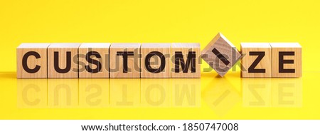 customize word written on wood block. customize word is made of wooden building blocks lying on the yellow table. customize, business concept, yellow background
