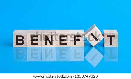 Text benefit on wood cube block, stock investment concept. The text benefit is written on the cubes in black letters, the cubes are located on a blue glass surface