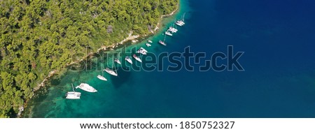 Aerial drone ultra wide photo of safe small fjord harbour of Mplo near bay of Panormos a popular yacht and sailboat anchorage with calm sea covered with pine trees, Skopelos island, Sporades, Greece