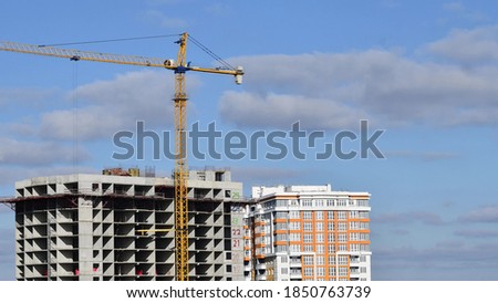 Construction site with big tower crane and cloudscape as background. Under construction concept of real estate development. Heavy construction machinery