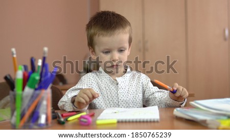 A handsome three year old boy sits at his desk in the class and thinks about the answer. Preschool education. 4k