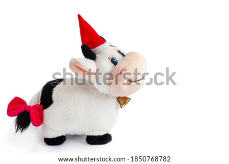 toy-soft cow in a Santa hat and a bow on the tail isolated on a white background