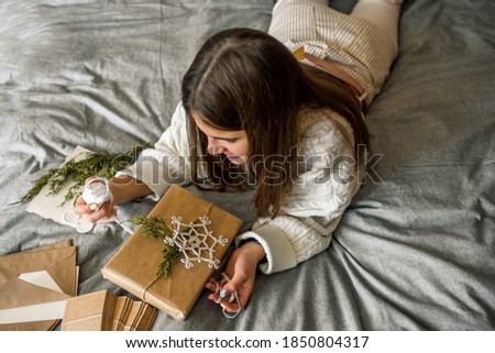 Girl wrapping gifts on desk with Christmas decoration. Flat lay, top view.Gift in a box, a letter in a craft envelope