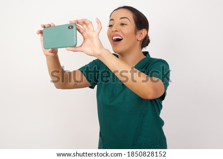 Young arab doctor surgeon woman over isolated white background taking a selfie to post it on social media or having a video call with friends. Royalty-Free Stock Photo #1850828152
