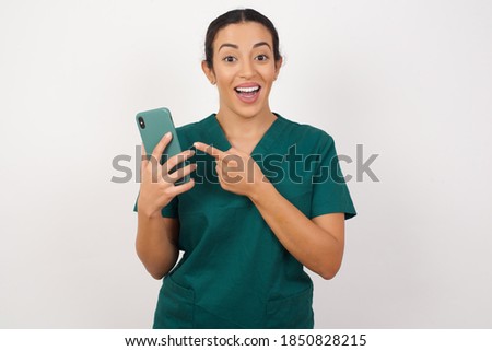 Portrait of Young arab doctor surgeon woman over isolated white background holding in hands showing new cell,