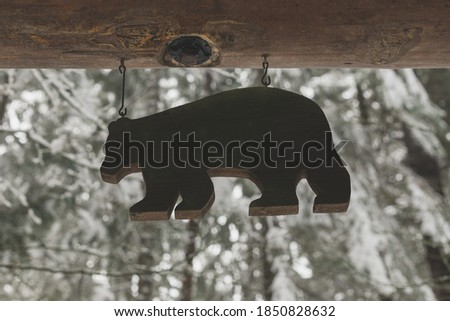 Wood Bear Sign Hanging Outside with a Snowy, Winter Scene in Background