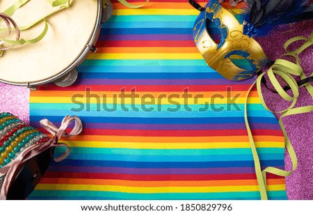 Masks, streamers, musical instruments of the Brazilian carnival, on a colorful surface, top view.