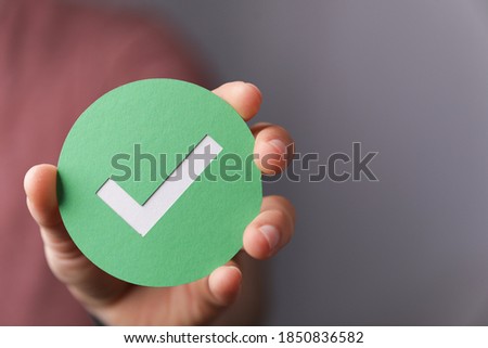 A hand holding a green paper with the checkmark sign on it Royalty-Free Stock Photo #1850836582