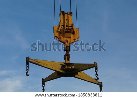Selective focused, steel crane hook hanging with metal sling for moving, lifting heavy object. Blue sky background. Concept of crane hook, mover, crane hook, industrial.                             