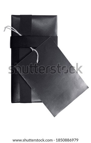 Black gift box with black ribbon and label tag isolated over white background