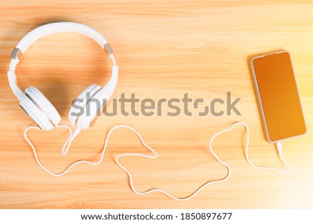 White Stereo headphones with Smartphone on wooden table isolated on white background. Top view