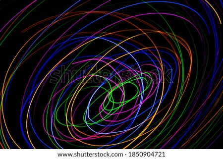 Multi color light painting photography, swirl and curve of blue, green and red light against a black background