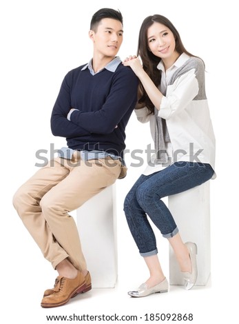 Portrait of young attractive Asian couple sitting on a box, full length portrait isolated on white background.