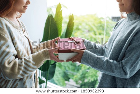 Closeup image of a young women giving friend a gift box 