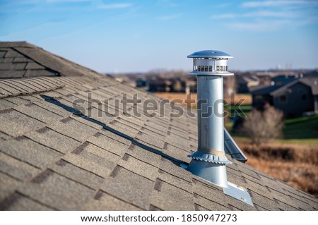 side view of a Galvanized metal chimney exhaust on  asphalt roof with a rain cap Royalty-Free Stock Photo #1850947273