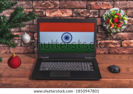 Christmas, new year's composition. Branches of the tree are decorated with Christmas balls on the background of a laptop with the image of the flag of India