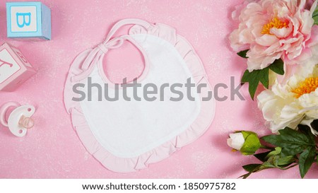 Baby bib nursery clothing mom bloggers desktop mockups with peonie floers on pink textured background. Top view blog hero header creative composition flat lay. Negative copy space mock up.