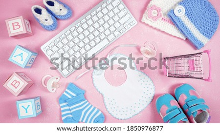 Baby nursery clothing mom bloggers desktop workspace with pink and blue accessories and shopping cart on pink textured background. Top view blog hero header creative composition flat lay.