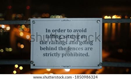 a warning sign for tourists or visitors with a backdrop of urban lights at night