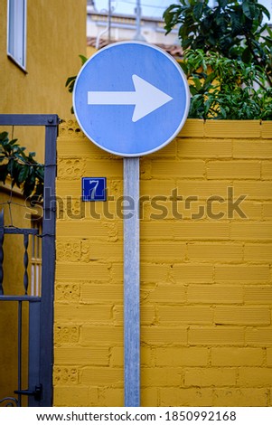 Mandatory direction sign on a yellow wall with a plate with the number seven.