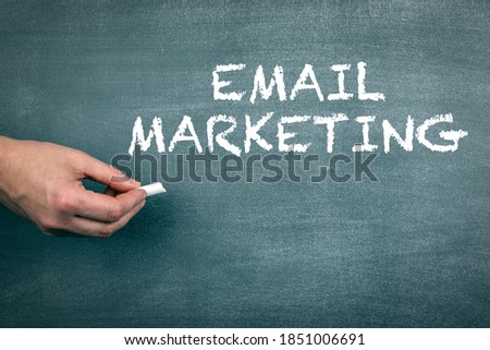 Email Marketing concept. Hand with white chalk. Gray chalk board background 