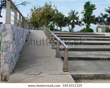 Disabled ramp installed in the public park beside the stair. Standard construction for handicap and old aged people in Asia.  Royalty-Free Stock Photo #1851011329