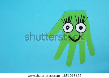Funny green hand shaped monster on light blue background, top view with space for text. Halloween decoration