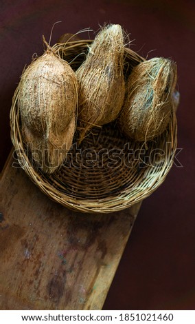 Hairy coconut in a cane basket on a wooden plank