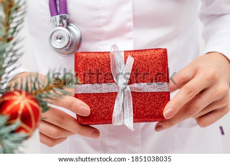Close-up of a doctor's hands holding a red gift box.Christmas, New Year and medical concept.