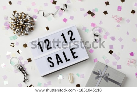 12.12 sale text on white lightbox, holiday ribbon and box on white background. Online shopping, singles day sale concept. Top view copy space 
