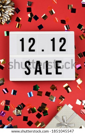 12.12 sale text on white lightbox, holiday ribbon and box on red background. Online shopping, singles day sale concept. Top view copy space 