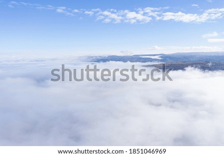 Aerial drone shot of flying above clouds in a misty morning