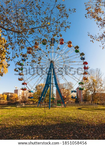 A front view of multi-colored Ferris wheel without people. Sunny day in a town park