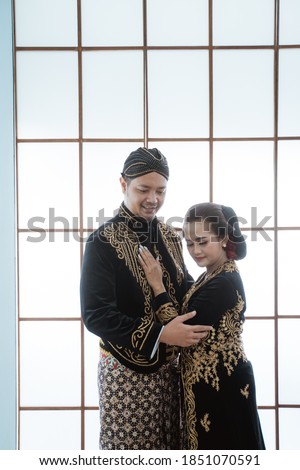 Portrait happy men and women wearing javanese traditional clothes. Couple concept photo standing by the window