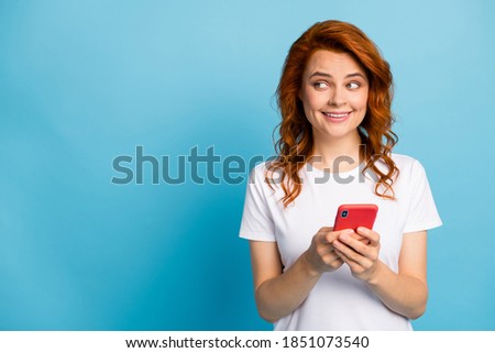 Photo portrait of woman holding phone in two hands looking at blank space isolated on pastel blue colored background