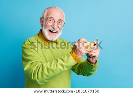 Photo of amazed grandfather hold telephone open mouth crazy wear eyeglasses green pullover isolated blue color background