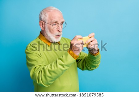 Profile photo of shocked grandpa hold telephone watch movie wear glasses green pullover isolated blue color background
