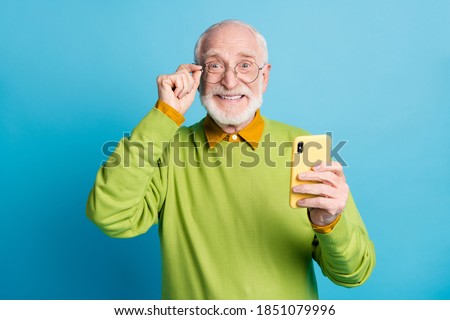 Photo of retired grandpa hold telephone eyewear look camera wear spectacles green sweater isolated blue color background Royalty-Free Stock Photo #1851079996