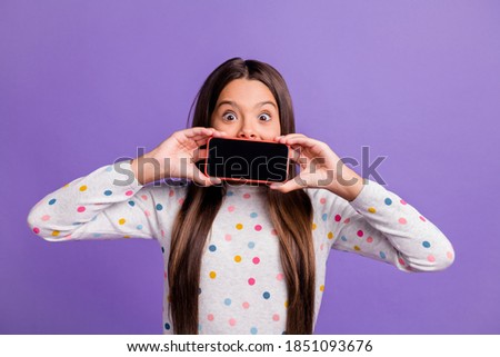 Photo portrait of shocked girl covering mouth with phone with blank space isolated on bright purple colored background