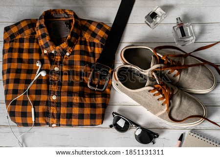 Stylish men's casual outfits on wood board background, essential leisure items for the tourist