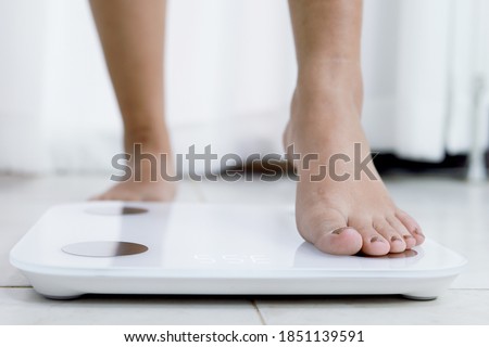 feet standing on electronic scales for weight control. Measurement instrument in kilogram for a diet control Royalty-Free Stock Photo #1851139591